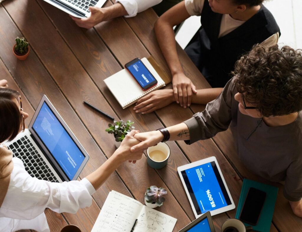 Sobre A diverse group of professionals brainstorming in a modern workspace with laptops and notebooks.